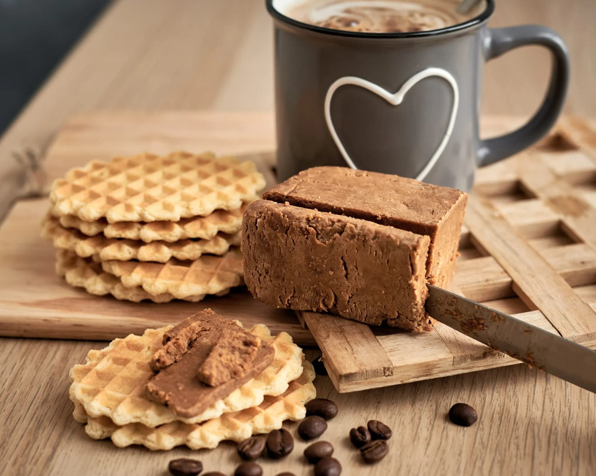 Gudbrandsdalsost fudge being sliced next to waffles and coffee in a mug with a heart.
